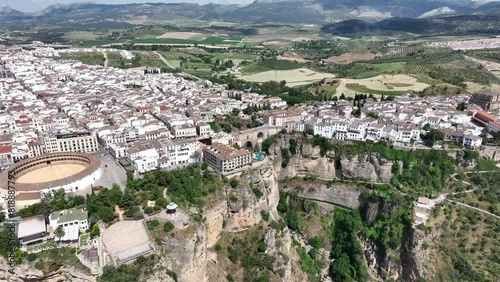 Cinematic aerial video of historic houses built on the edge of the cliff with bridge and waterfall in Ronda, Spain