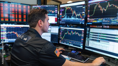 Trader monitoring financial graphs on multiple screens in a busy trading floor