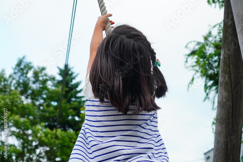 ターザンロープで遊ぶ小学生の頃3年生の女の子の後ろ姿 photo