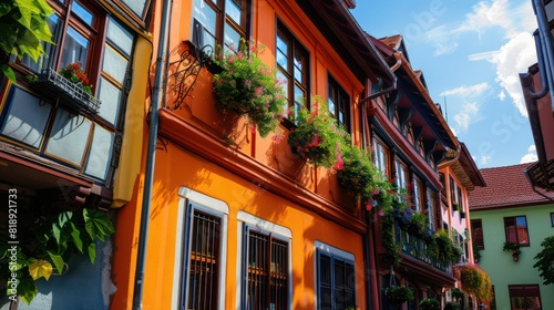 Orange and brown traditional half-timbered houses with windows decorated with flowering plants under a clear sky photo