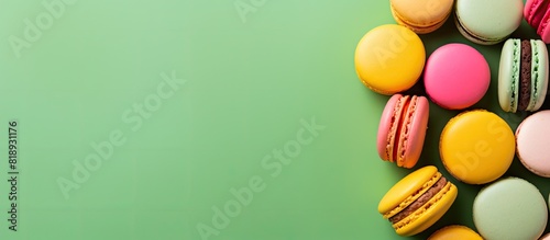 Top view of macarons or macaroons cookies arranged on a green background with a colorful and vibrant mix of colors in the image. Copyspace image