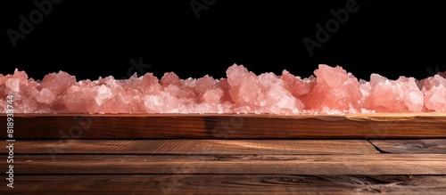A copy space image featuring Himalayan pink salt spread across a rustic wooden table