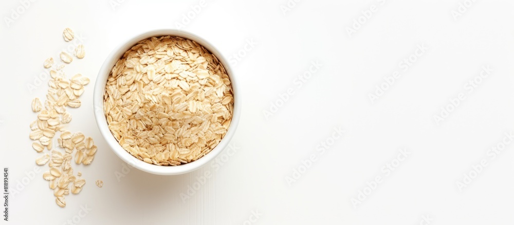 A top down view of a bowl containing rolled oats sits on a white table offering empty space for placing an image or text. Copyspace image A top down view of a bowl containing rolled oats sits on a white table offering empty space for placing an image or text. Copyspace image