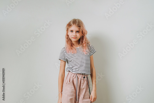 A 9-year-old girl stands against the wall.