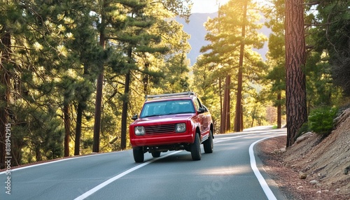 A red pickup truck is driving down a road in the woods
