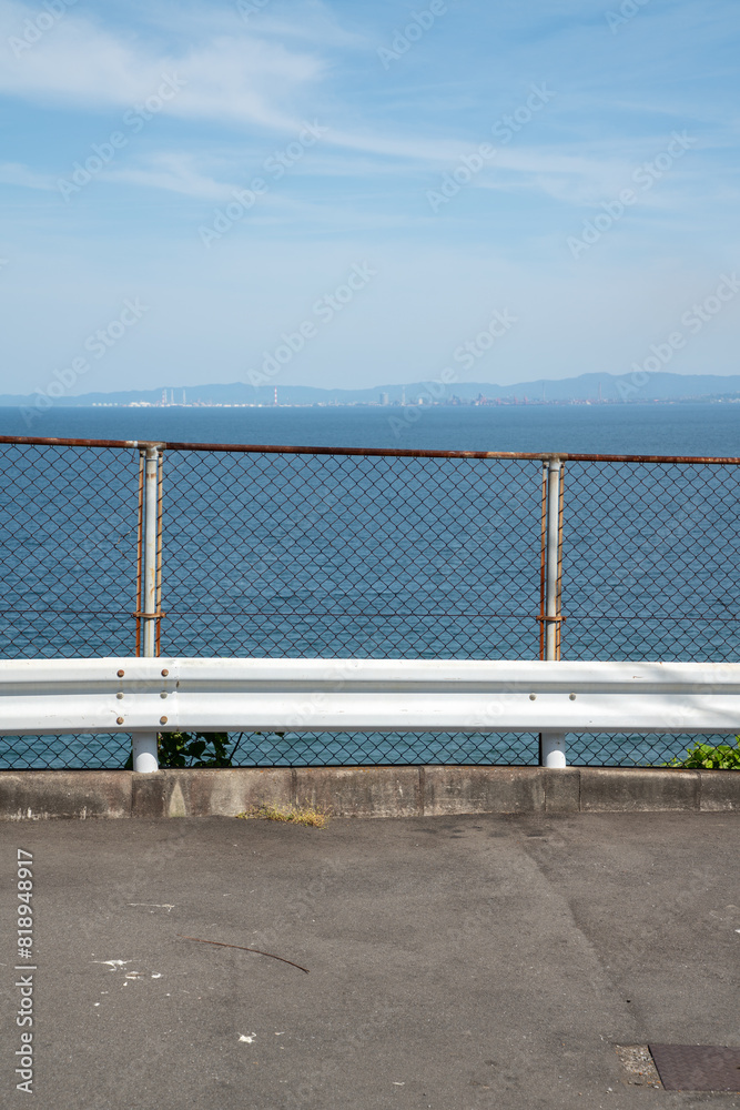 Fototapeta premium フェンス越しに海が見える坂道