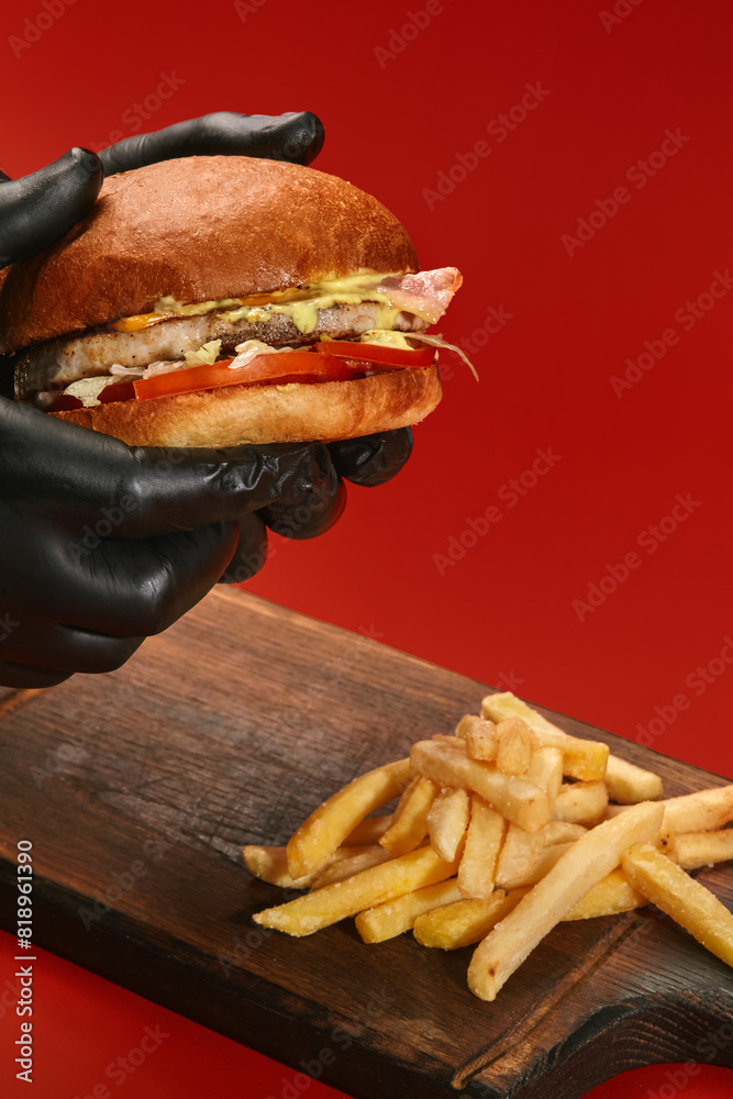 Hands holding burger with chicken patty on red background