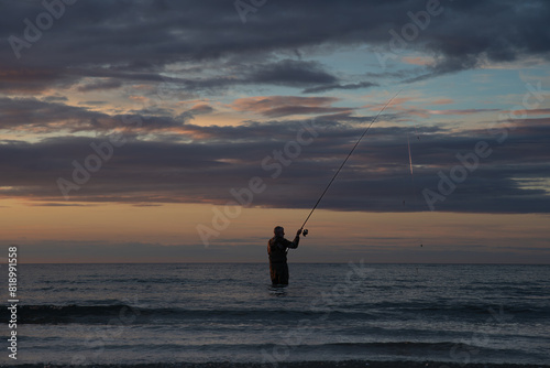 Pêcheur en surfcasting sur une plage de Bretagne en soirée - France