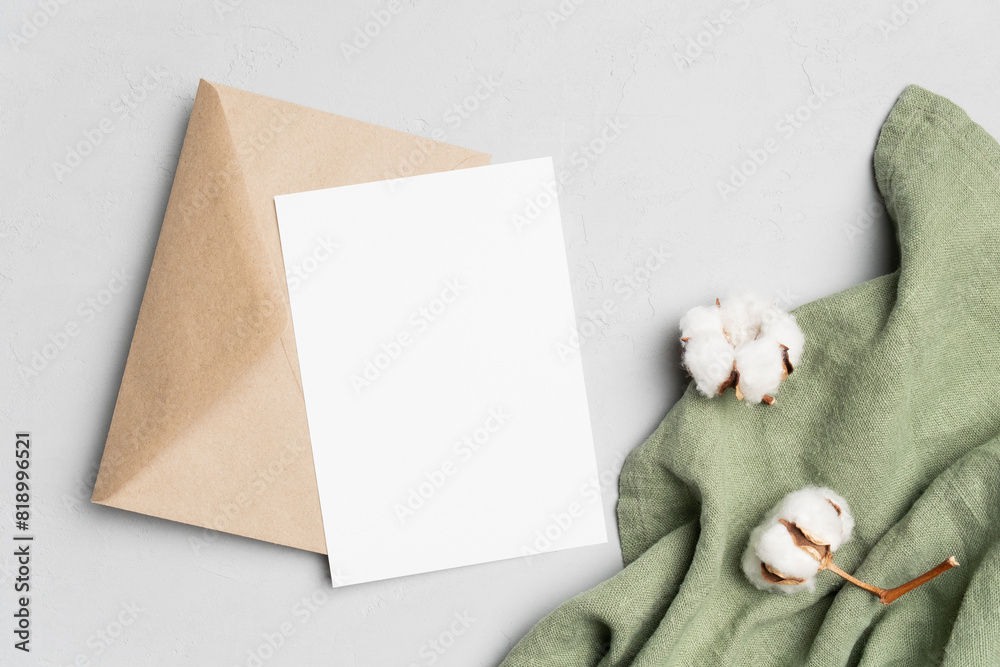 Fototapeta premium Invitation card mockup with envelope and cotton flowers decor, blank card with copy space, top view