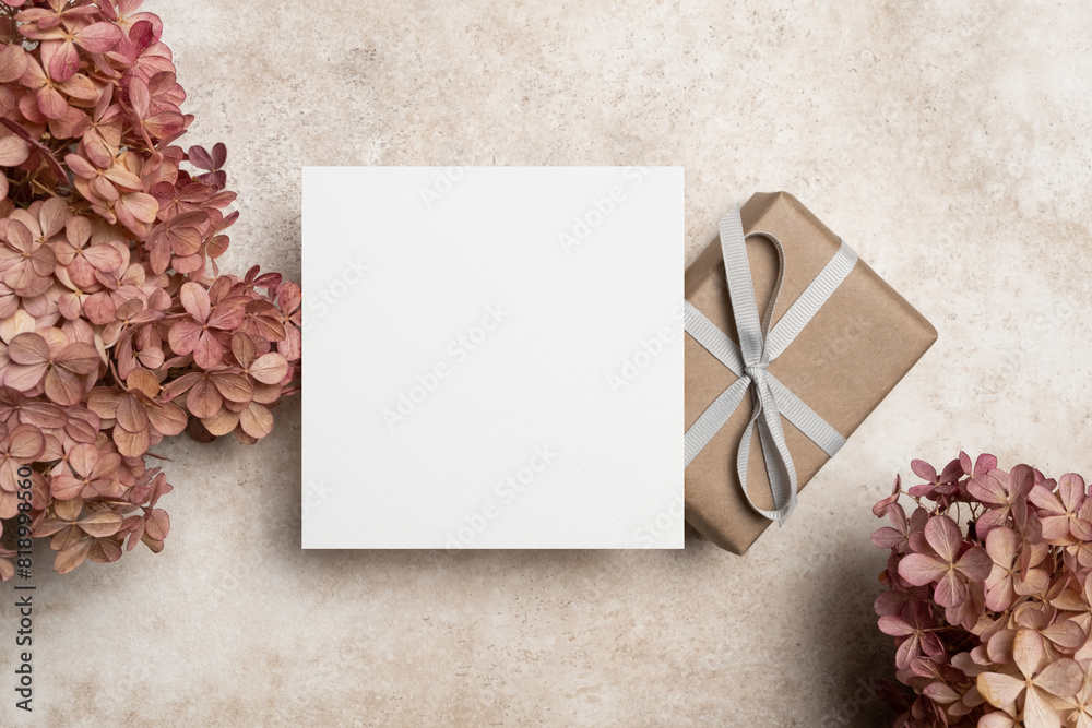 Blank square paper card mockup with gift box and dry hydrangea flowers decor, white card with copy space