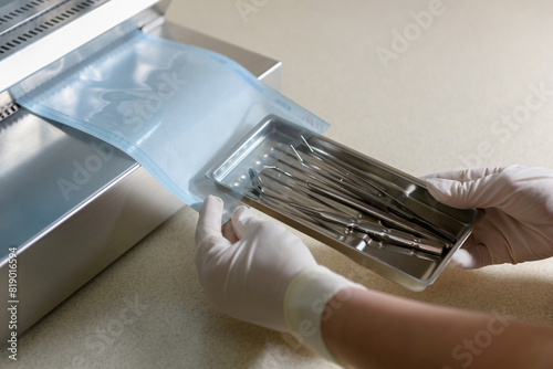 Sterilization of dental medical instruments. Dental assistant packs dental equipment into plastic bags for sterilization using a sterilization roll packaging machine for sterilized dental instruments.