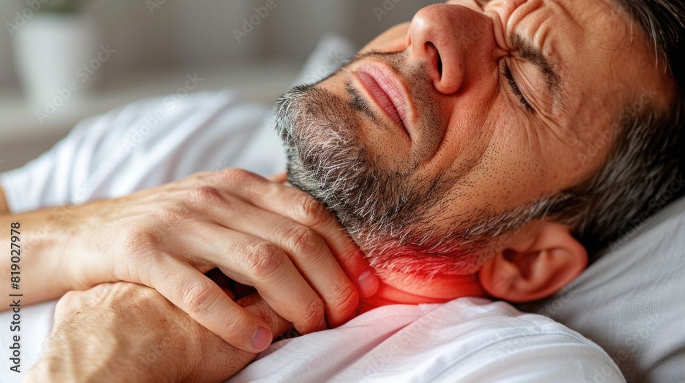 A man with a red neck and a red mark on his ear. He is in pain and is holding his neck A man with a red neck and a red mark on his ear. He is in pain and is holding his neck