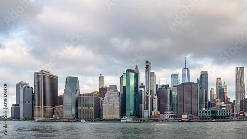 New York city skyline time lapse - Manhattan under dramatic sky with stormy moving clouds hyper lapse. Waterfront cityscape of urban metropolis with tall buildings in the United States of America.
