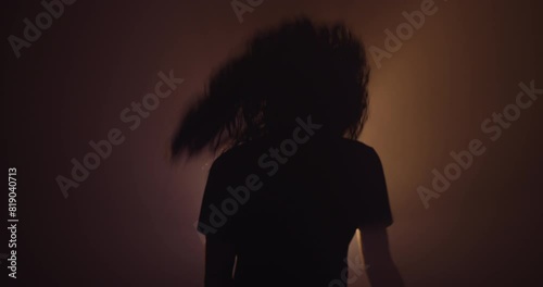 Silhouette of a person with long hair head banging 