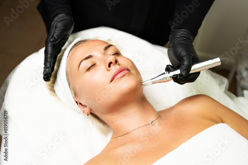 Microneedle RF lifting procedure. A cosmetologist performs a facial rejuvenation procedure on a woman. Hardware cosmetology.