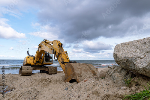 Excavator at sea. Construction equipment on the seashore. Construction of coastal fortifications.