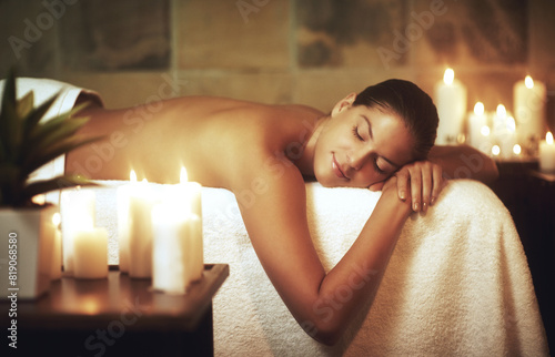 Woman, relax and massage bed in salon for glow, wellness and cosmetics with candles. Zen, beauty and sleeping with peace after aromatherapy, deep tissue and stress relief in spa with oil for luxury
