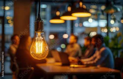 Group of People Sitting Around Table With Light Bulb in Background