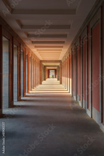 The hallway is long with red walls and columns, creating a bold aesthetic