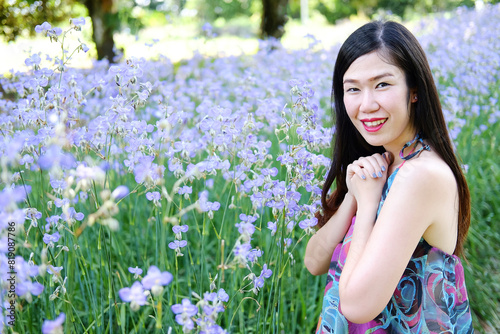 Beautiful Asian woman is smiling and relaxing in blooming purple Murdannia giganteum flowers field © cocorattanakorn