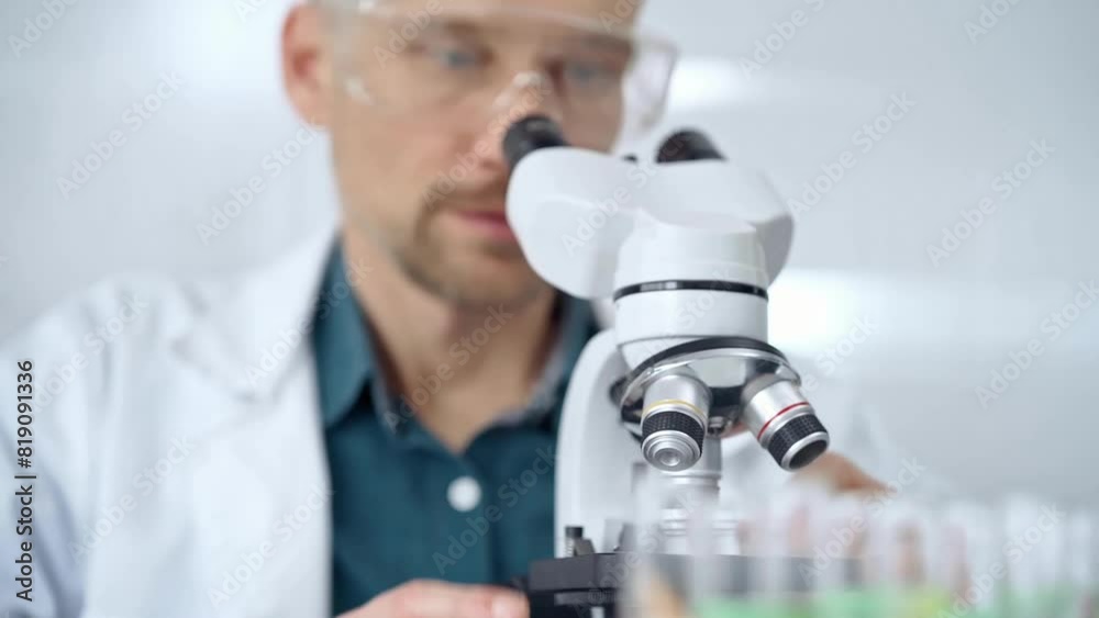 Man scientist with protective glasses using microscope in laboratory. Microbiology science concept Man scientist with protective glasses using microscope in laboratory. Microbiology science concept