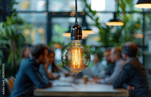 Group of People Sitting at Table Under Hanging Light Bulb