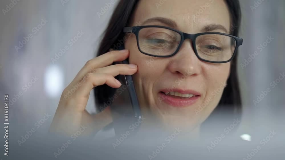 Cheerful smiling woman with glasses using a mobile phone, blurred background. Lifestyle and business concepts Cheerful smiling woman with glasses using a mobile phone, blurred background. Lifestyle and business concepts