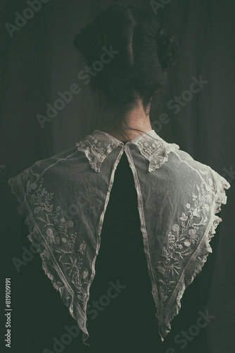 woman with embroidered collar and vintage black dress from behind in romantic attitude II