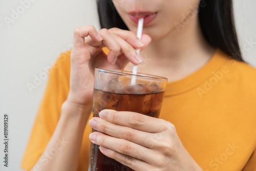 Fotografía Smile happy thirsty asian young woman drinking or sip, holding glass of ice sparkling soda, cola water with straw, refreshness people, isolated on background