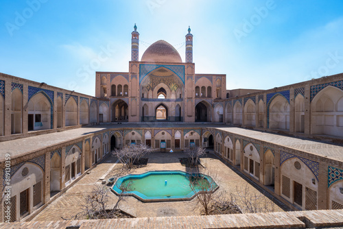 The peaceful courtyard of the Agha Bozog Mosque features a reflecting pool and showcases Persian architecture. Symmetrical arches and detailed tiles add depth. Tehran, Iran. photo