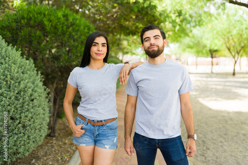 Confident young hispanic couple in grey t-shirts posing in a lush park for branding mockups © AntonioDiaz