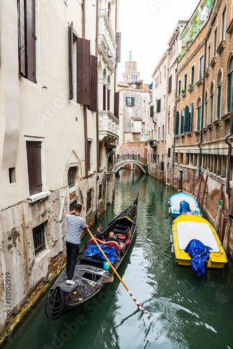 Принти на полотні A Gondolier in the city of Venice, Italy maneuvering his gondola in a canal