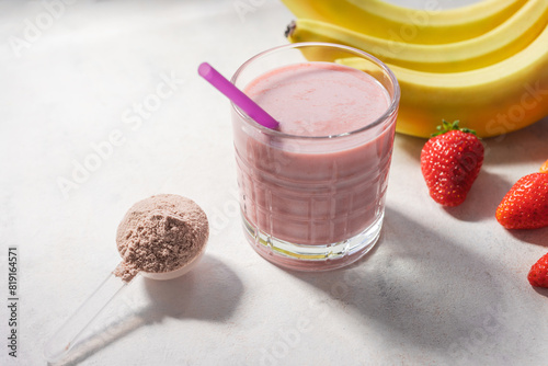 Strawberry and banana smoothie, protein drink in a glass, measuring scoop with whey protein powder, blended cocktail, milkshake photo