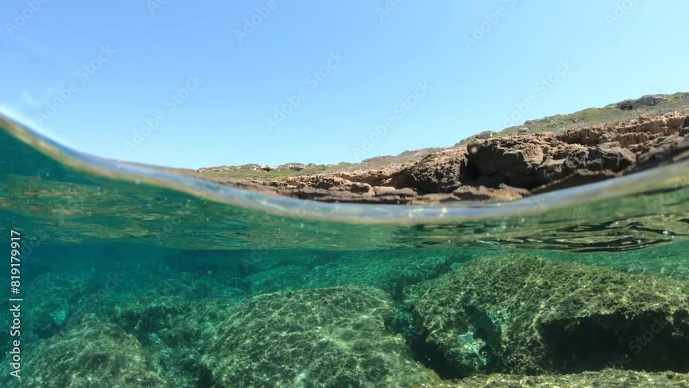 Split underwater view of a rocky shore in Sardinia, Italy Split underwater view of a rocky shore in Sardinia, Italy