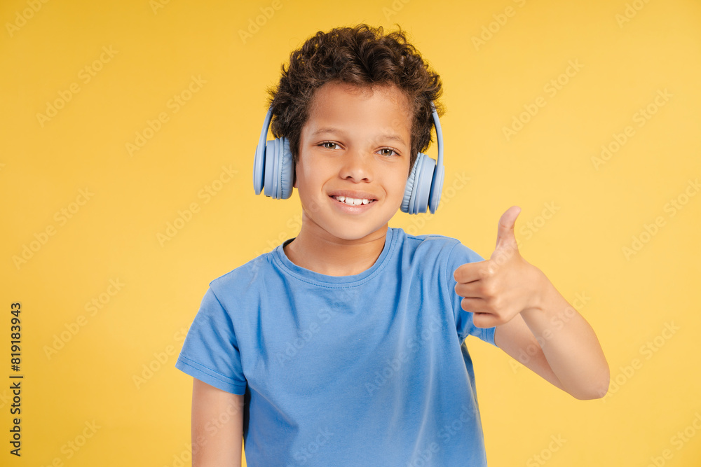 Attractive smiling little African American boy wearing headphones listening to music Attractive smiling little African American boy wearing headphones listening to music