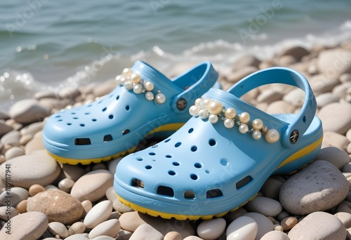  A pair of light blue crocs-style sandals on a sandy beach.