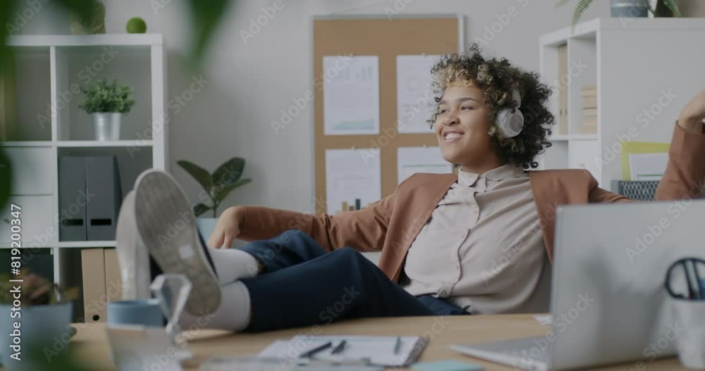 Loop of creative African American employee dancing relaxing in office listening to music with headphones in office room. Businesswoman and workplace fun concept. Loop of creative African American employee dancing relaxing in office listening to music with headphones in office room. Businesswoman and workplace fun concept.