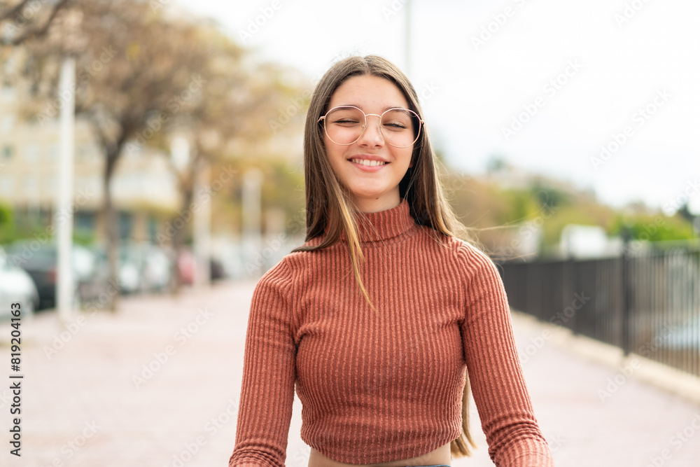 Teenager girl at outdoors With glasses and happy expression