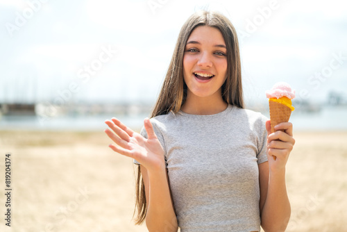 Teenager girl with a cornet ice cream at outdoors with shocked facial expression photo
