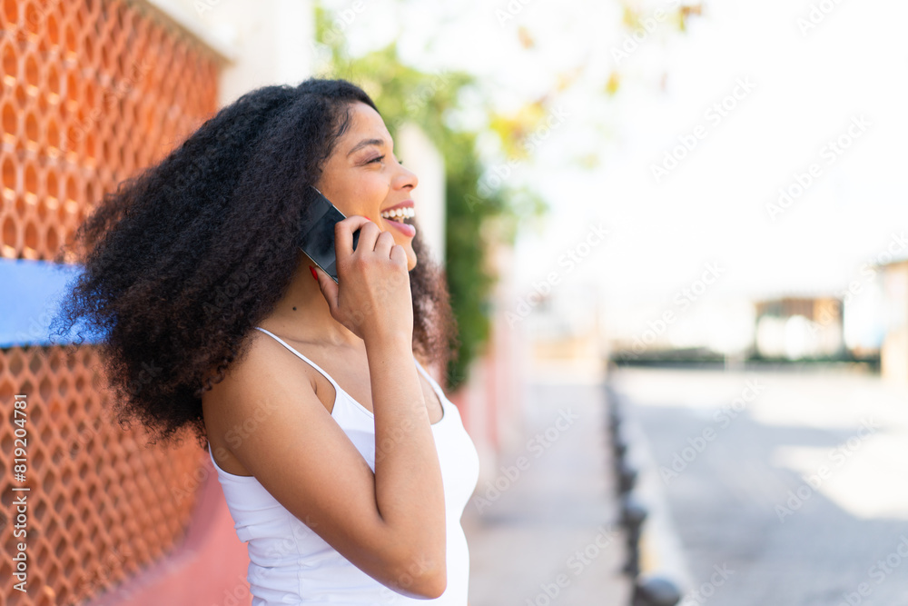 Young African American woman at outdoors keeping a conversation with the mobile phone Young African American woman at outdoors keeping a conversation with the mobile phone