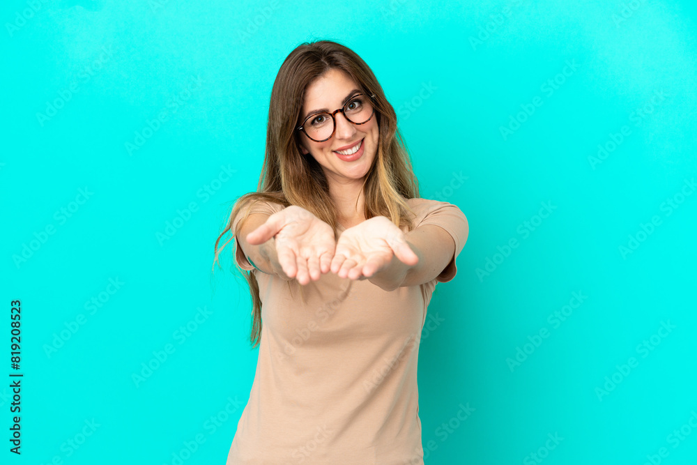 Young caucasian woman isolated on blue background holding copyspace imaginary on the palm to insert an ad Young caucasian woman isolated on blue background holding copyspace imaginary on the palm to insert an ad