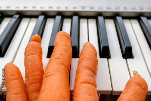 Five carrots on synthesizer keyboard as a symbol of incorrect piano hand posture