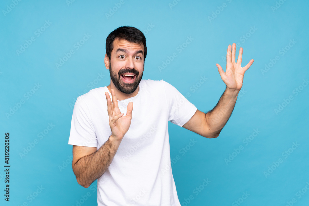Young man with beard  over isolated blue background nervous and scared