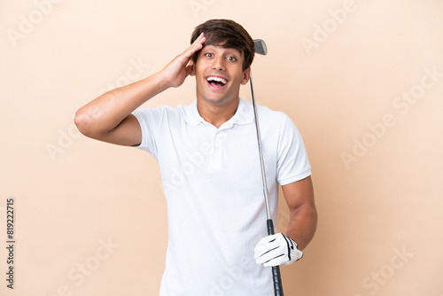 Young golfer player man isolated on ocher background with surprise expression