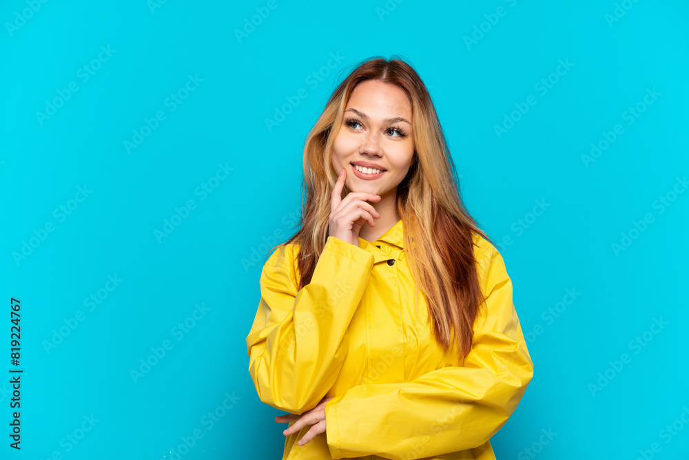 Teenager girl wearing a rainproof coat over isolated blue background thinking an idea while looking up Teenager girl wearing a rainproof coat over isolated blue background thinking an idea while looking up