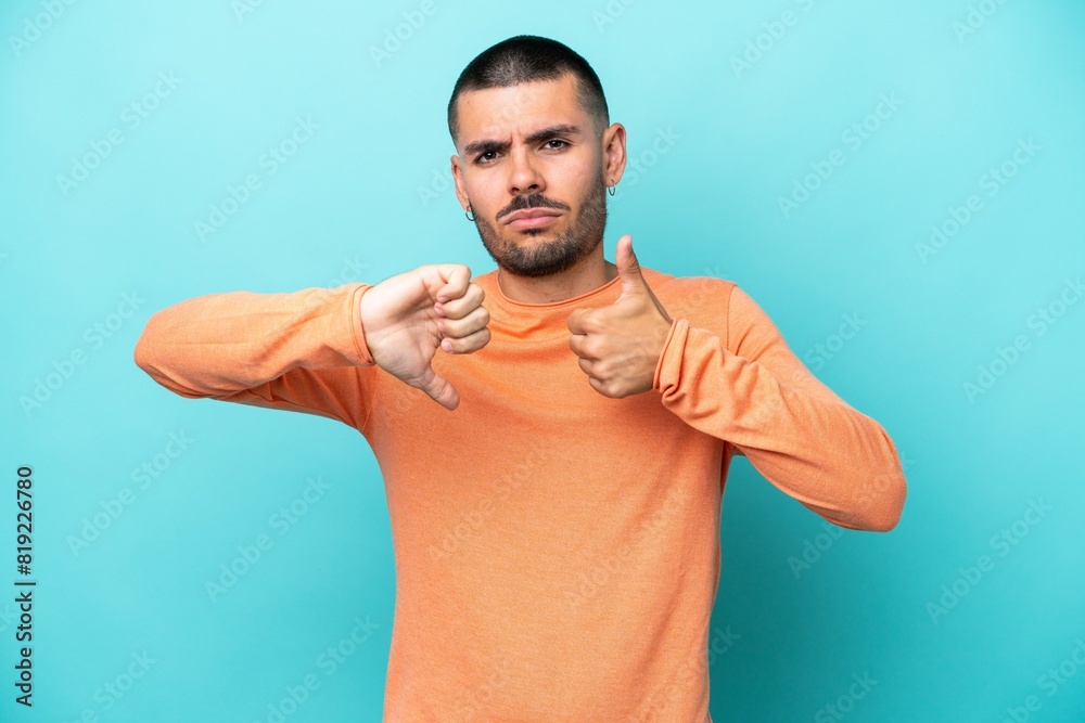 Young caucasian man isolated on blue background making good-bad sign. Undecided between yes or not Young caucasian man isolated on blue background making good-bad sign. Undecided between yes or not