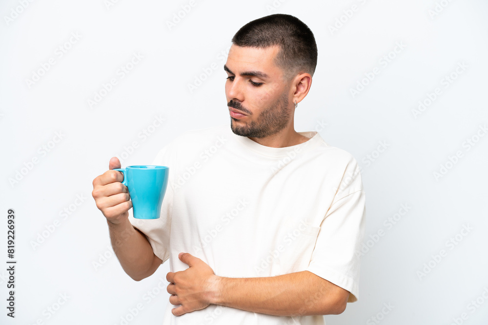 Young caucasian man holding cup of coffee isolated white background with sad expression Young caucasian man holding cup of coffee isolated white background with sad expression
