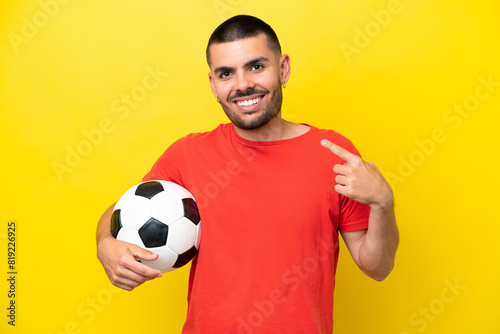 Young caucasian man playing soccer isolated on yellow background giving a thumbs up gesture © luismolinero