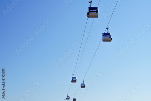 Cabins ride on a cable car against the sky. View from below. Funicular