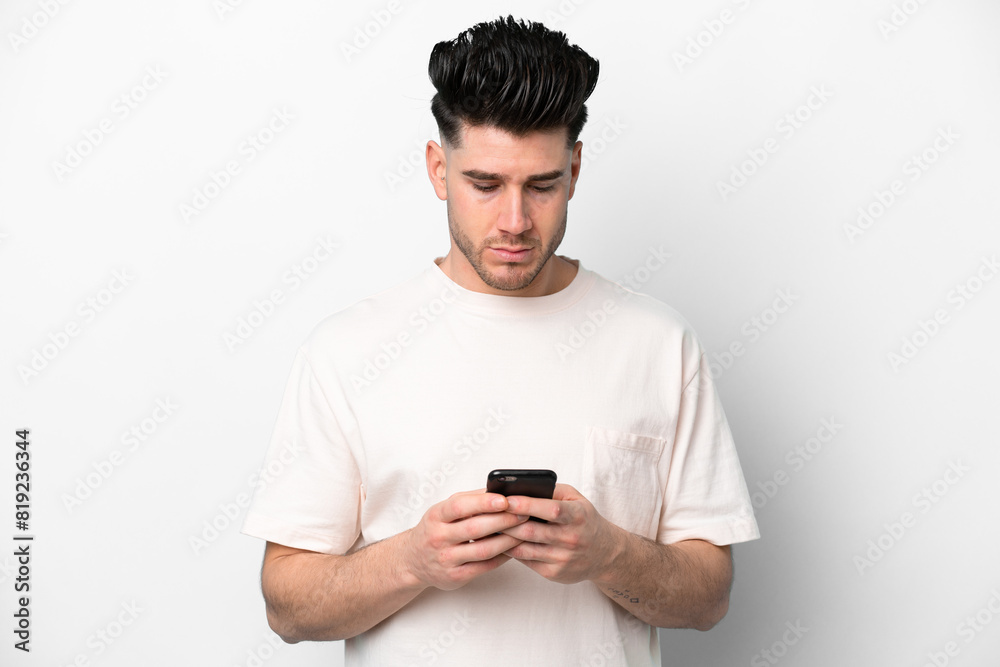 Young caucasian man isolated on white background using mobile phone